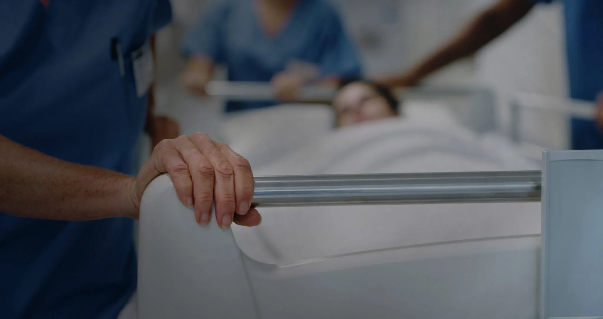 A healthcare worker's hand gripping a hospital bed rail, representing a high-touch surface protected by Prescientx’s self-disinfecting antimicrobial technology.