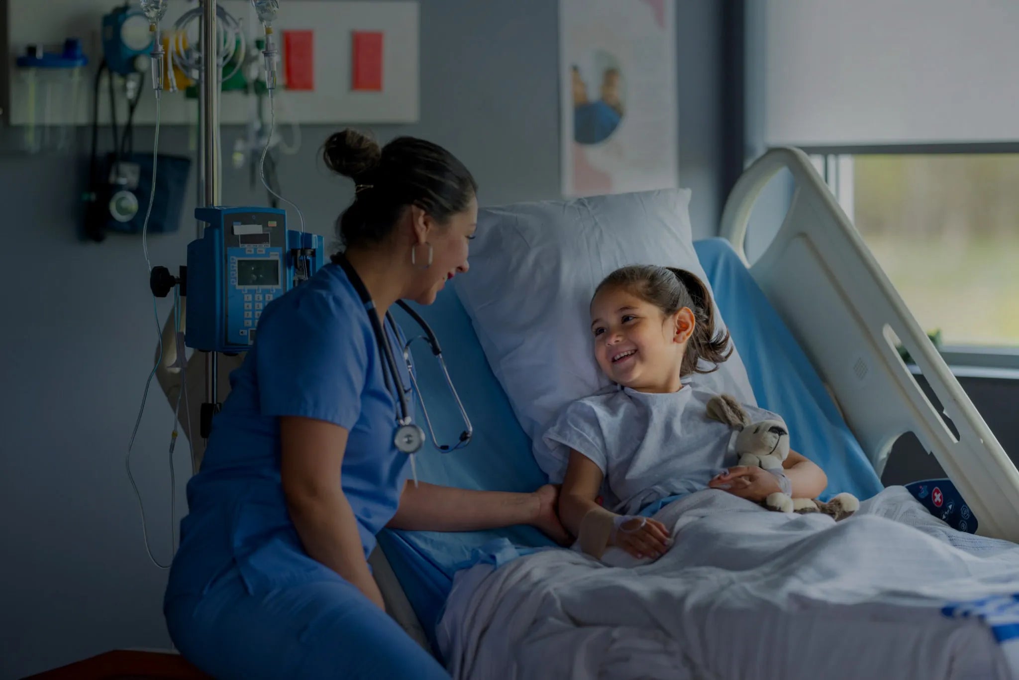 A nurse smiling at a young patient in a hospital bed, symbolizing the safety and comfort enabled by continuous air disinfection from Prescientx.
