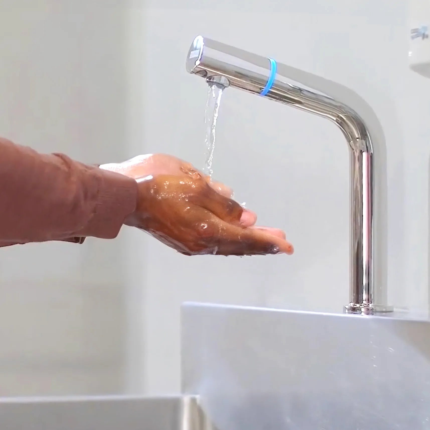 Hands being washed under a self-cleaning sink designed to meet infection prevention standards in healthcare facilities.