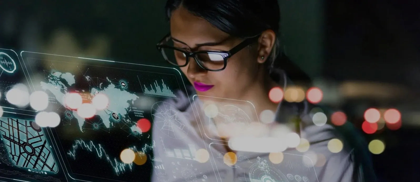 Image of woman wearing glasses, sitting in front of futuristic screens displaying scientific data.